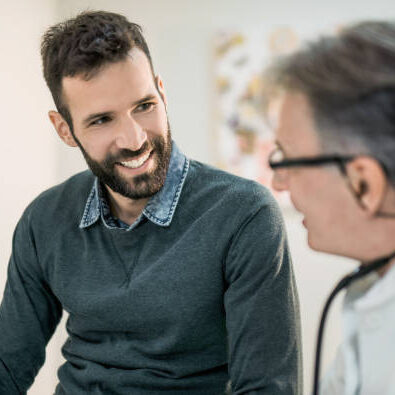 Happy mid adult male patient talking with his doctor.